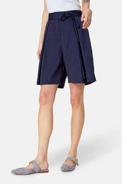 Blauwe bermuda met krijtstreep van Le Fabuleux Marcel de Bruxelles, met strikceintuur en Mary Jane-schoenen met zebraprint.
