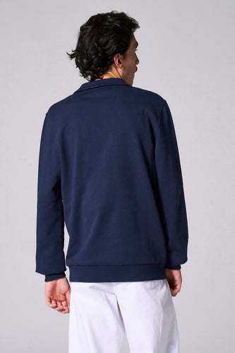 Rug van man in marineblauw sweatshirt en witte broek.
