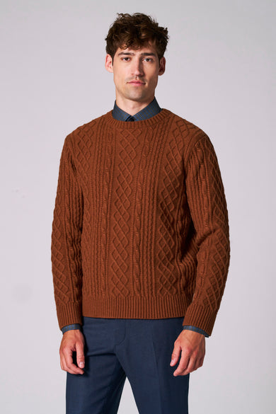 Bruine trui met ronde hals van Le Fabuleux Marcel de Bruxelles, met kabelpatroon en zichtbaar overhemd eronder, gecombineerd met een blauwe pantalon.
