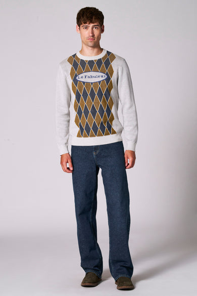 Rechte, middenblauwe denim jeans van Le Fabuleux Marcel de Bruxelles, gecombineerd met bruine schoenen en een trui met ruitpatroon.