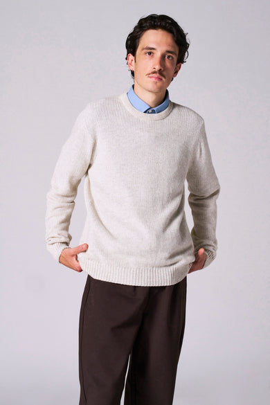 Beige ronde hals trui van Le Fabuleux Marcel de Bruxelles, gedragen over een blauw overhemd en met bruine broek.
