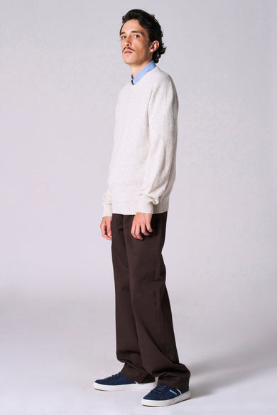 Beige trui met ronde hals van Le Fabuleux Marcel de Bruxelles, met lange mouwen en gedragen met een blauw overhemd en bruine broek.

