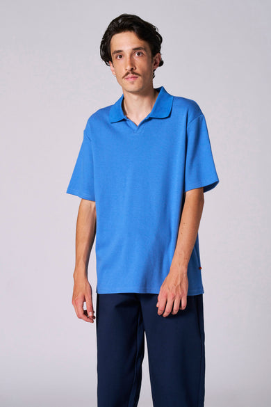 Polo bleu à manches courtes de Le Fabuleux Marcel de Bruxelles, avec une subtile texture et un pantalon bleu marine.