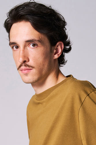 Beige T-shirt met lange mouwen van Le Fabuleux Marcel de Bruxelles, gedragen door een man met een snor.