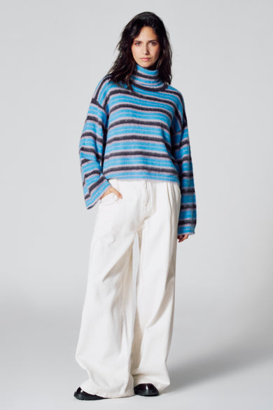 T-shirt à col rond bleu de Le Fabuleux Marcel de Bruxelles, avec des rayures horizontales et associé à un pantalon blanc.