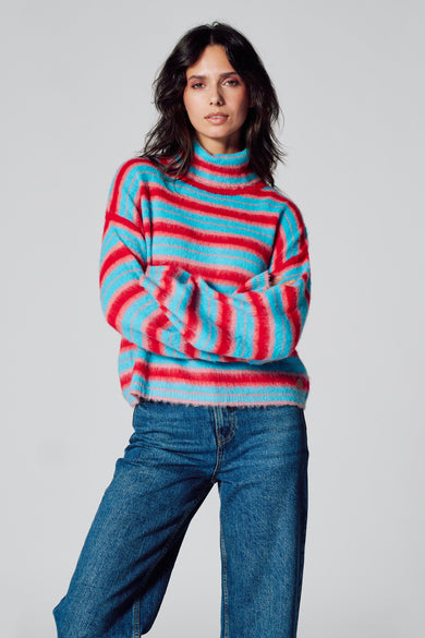 Sweat-shirt multicolore à col montant de Le Fabuleux Marcel de Bruxelles, avec des rayures horizontales et associé à un jean bleu marine.