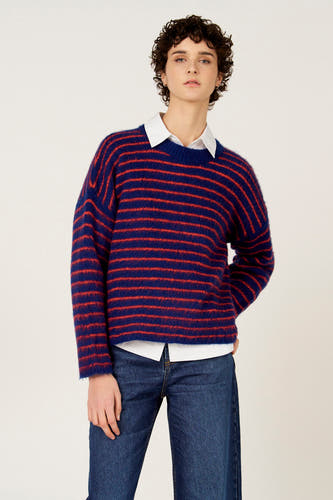 Veelkleurige trui met ronde hals van Le Fabuleux Marcel de Bruxelles, met horizontale strepen, gedragen over een wit overhemd met jeans.
