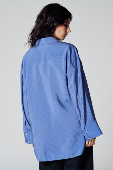 Chemise bleue à manches longues de Le Fabuleux Marcel de Bruxelles, avec des fines rayures et une fermeture à boutons.