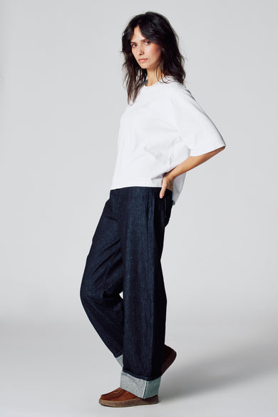 Wit T-shirt met korte mouwen van Le Fabuleux Marcel de Bruxelles, gedragen met wijde, donkere jeans en bruine schoenen.