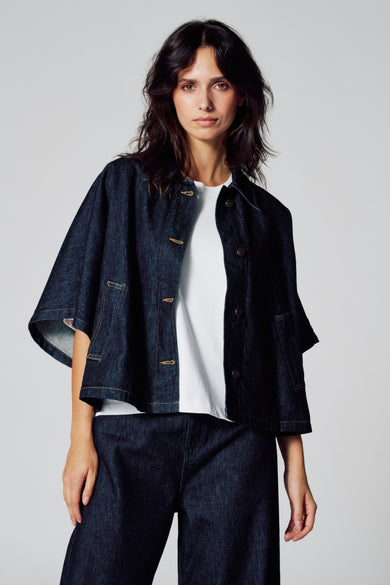 Manteau de denim bleu marine de Le Fabuleux Marcel de Bruxelles, porté sur un T-shirt blanc et un pantalon de denim.