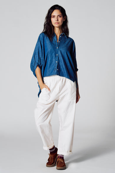 Donkerblauw denim hemd met korte mouwen van Le Fabuleux Marcel de Bruxelles, gedragen met witte broek en bruine schoenen.