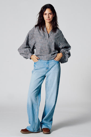 Multicolour blouse met lange mouwen van Le Fabuleux Marcel de Bruxelles, met een geruit patroon, gecombineerd met blauwe jeans en bruine schoenen.
