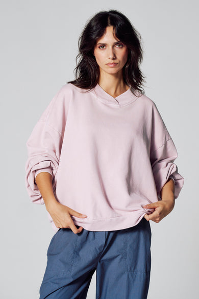 Gilet rose de Le Fabuleux Marcel de Bruxelles, avec des manches longues et un pantalon bleu.