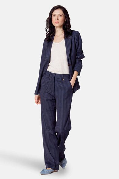 Blauwe blazer van Le Fabuleux Marcel de Bruxelles, met krijtstrepen, gecombineerd met een losse broek en een shirt.
