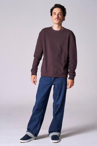 Pull marron de Le Fabuleux Marcel de Bruxelles, à longues manches, associé à un jeans foncé et des chaussures bleues.