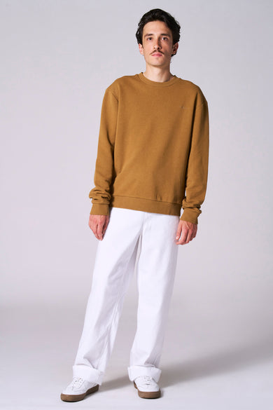Pull marron de Le Fabuleux Marcel de Bruxelles, associé à un pantalon blanc et des chaussures.
