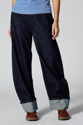 Donkerblauwe denim LE JEAN BALLOON van Le Fabuleux Marcel de Bruxelles, met omgeslagen broekspijpen en bruine schoenen.
