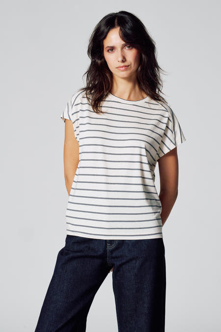 Beige T-shirt met korte mouwen van Le Fabuleux Marcel de Bruxelles, met horizontale donkerblauwe strepen, gedragen met een donkerblauwe jeans.
