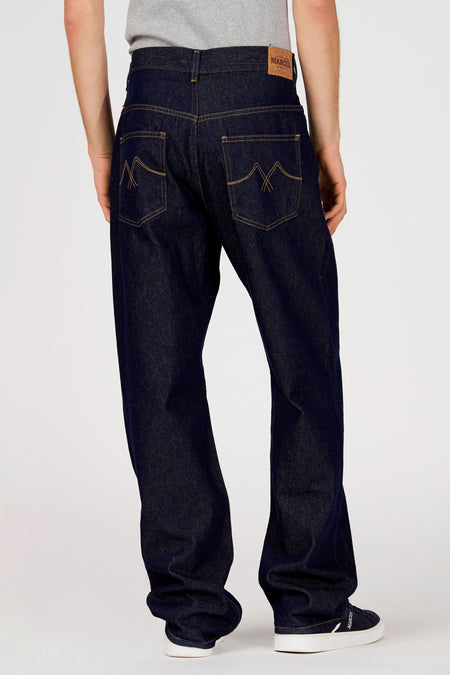Donkerblauwe straight jeans van Le Fabuleux Marcel de Bruxelles, met steekzakken aan de achterkant en schoenen met witte zolen.
