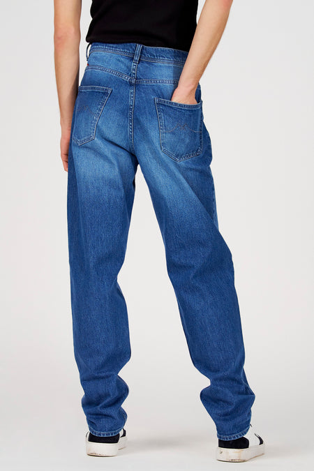 Blauwe straight jeans van Le Fabuleux Marcel de Bruxelles, met achterzakken en een hand in de rechterzak.
