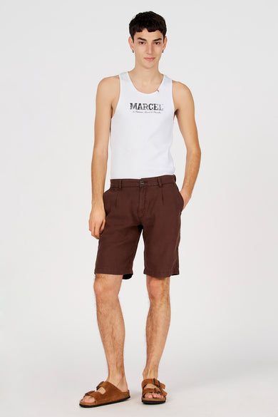 Bermuda marron de Le Fabuleux Marcel de Bruxelles, porté avec une chemise blanche et des sandales marron.