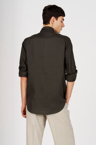 Groen hemd van Le Fabuleux Marcel de Bruxelles met opgerolde mouwen, van achteren gezien, gestyled met een gestreepte broek en oorbel.