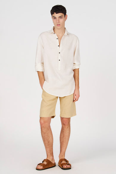 Chemise blanche en lin de Le Fabuleux Marcel de Bruxelles avec demi-patte de boutonnage, manches retroussées et boutons foncés.