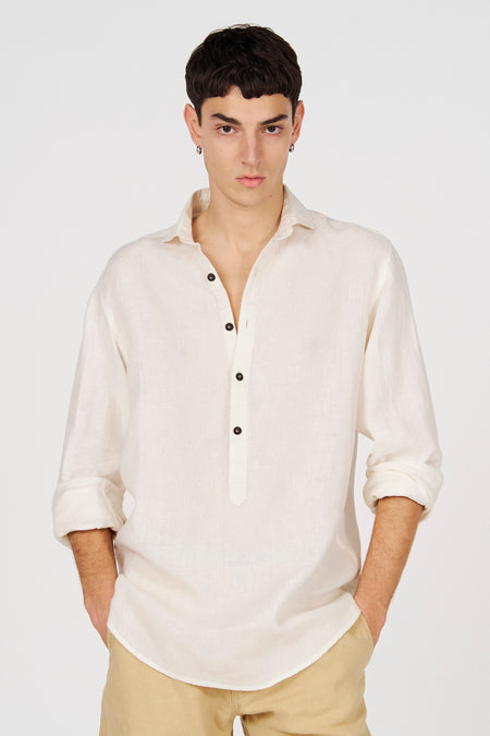 Chemise blanche en lin de Le Fabuleux Marcel de Bruxelles avec une demi-patte de boutonnage et des manches retroussées.