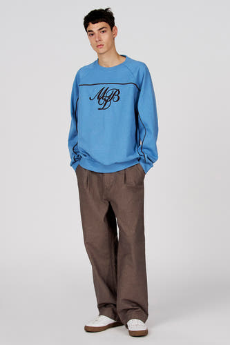 Pull bleu à col rond de Le Fabuleux Marcel de Bruxelles, avec détails noirs et texte sur la poitrine.