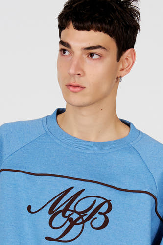 Pull bleu à col rond de Le Fabuleux Marcel de Bruxelles, avec une bande d'accent marron et un logo élégant.