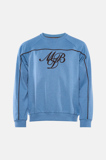 Pull bleu de Le Fabuleux Marcel de Bruxelles, avec des rayures marron et un logo brodé.