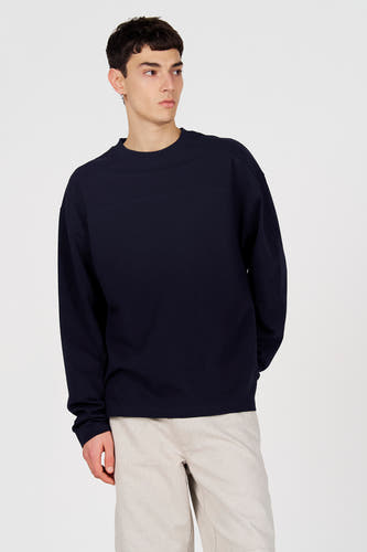 Pull bleu à col rond de Le Fabuleux Marcel de Bruxelles, porté avec un pantalon beige, vue arrière.