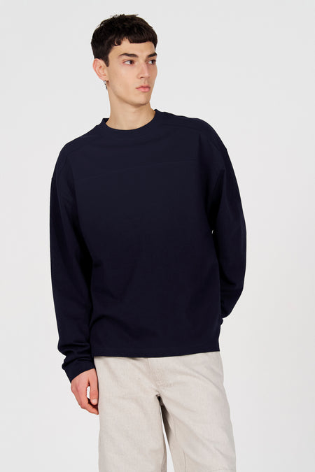 Pull bleu à col rond de Le Fabuleux Marcel de Bruxelles, porté avec un pantalon beige, vue arrière.