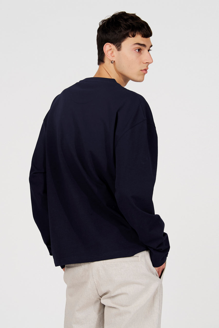 Blauwe sweater met ronde hals van Le Fabuleux Marcel de Bruxelles, gedragen met beige broek, achterkant.

