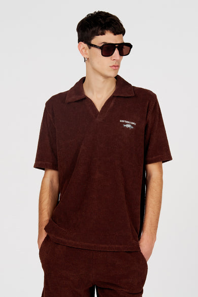 Bruine polo van Le Fabuleux Marcel de Bruxelles, met korte mouwen en "Keep Things Simple" tekst met vis motief.