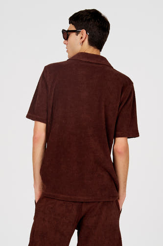 Bruine polo van Le Fabuleux Marcel de Bruxelles, met een uniek gestructureerd patroon, gezien van achteren.