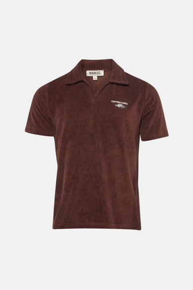 Bruine polo met korte mouwen van Le Fabuleux Marcel de Bruxelles, met een subtiel patroon en "Keep Things Simple"-motief.