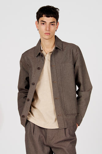 Bruine korte jas van Le Fabuleux Marcel de Bruxelles, met knoopsluiting en zakken, gedragen over een beige shirt.
