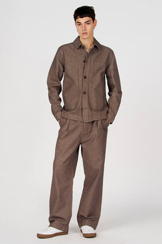 Bruine korte jas van Le Fabuleux Marcel de Bruxelles, met lange mouwen en bruine knopen, gedragen met een bijpassende bruine pantalon en witte schoenen.