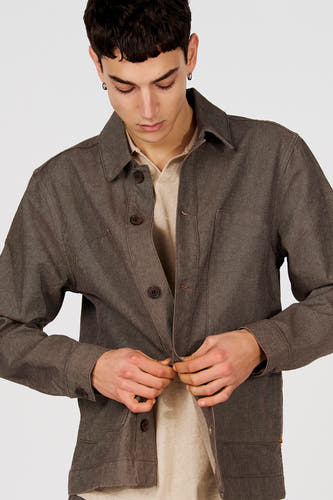 Bruine korte jas van Le Fabuleux Marcel de Bruxelles, met knoopsluiting en beige shirt eronder.
