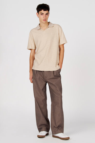 Polo grise de Le Fabuleux Marcel de Bruxelles, à manches courtes et portée avec un pantalon marron et des baskets blanches.