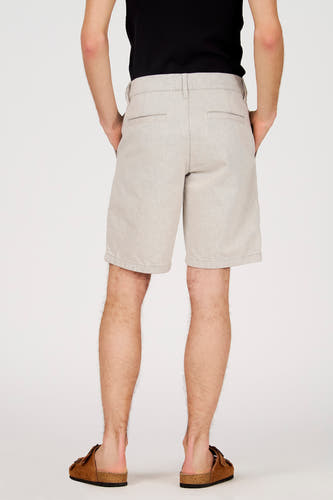 Ecru short van Le Fabuleux Marcel de Bruxelles, gezien van achteren, met steekzakken en bruine sandalen.
