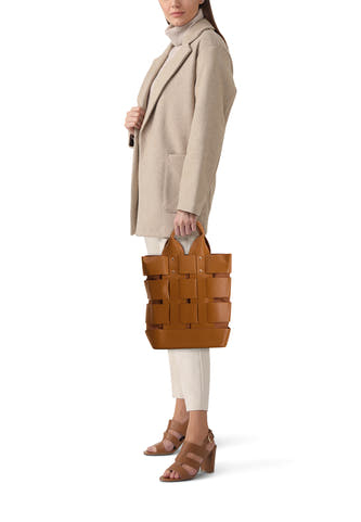 Bruine handtas van Le Fabuleux Marcel de Bruxelles, gedragen door een model met een beige jas en hakken.
