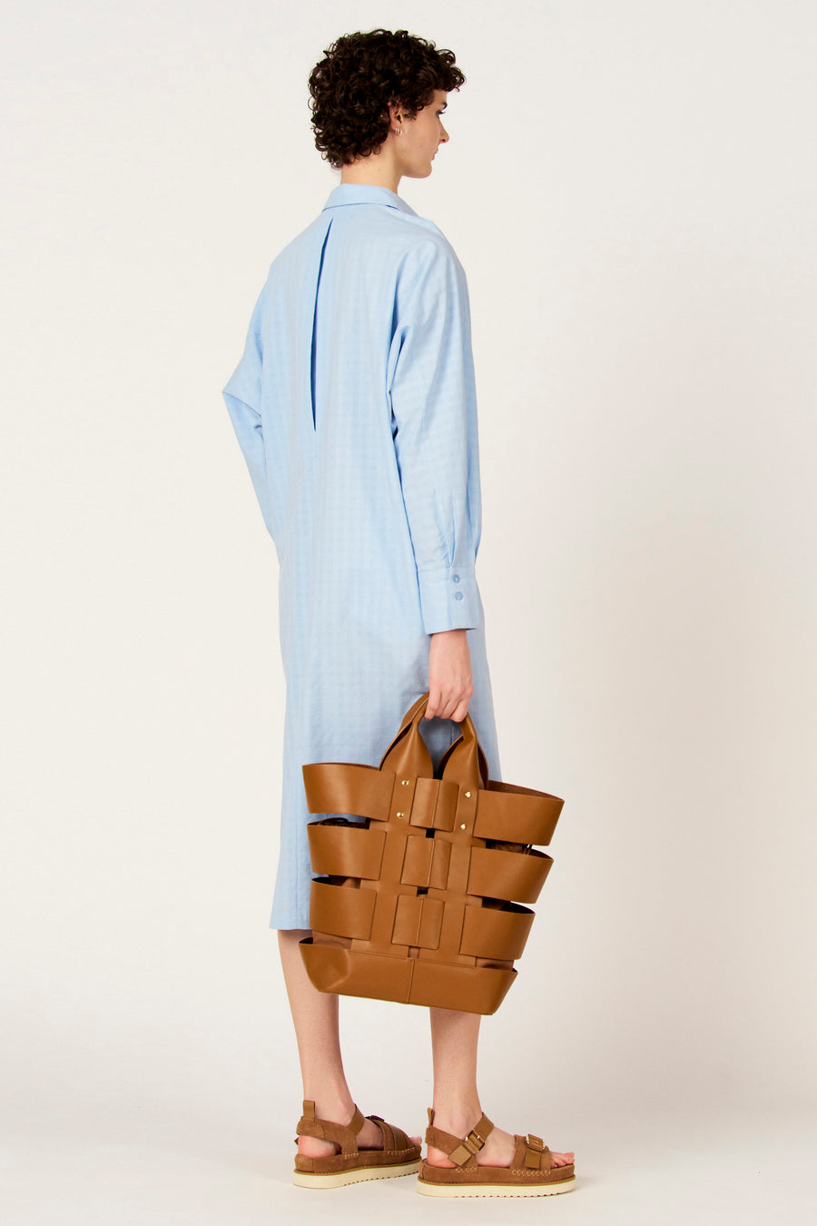 Bruine handtas van Le Fabuleux Marcel de Bruxelles, met een geweven ontwerp en bruine sandalen.
