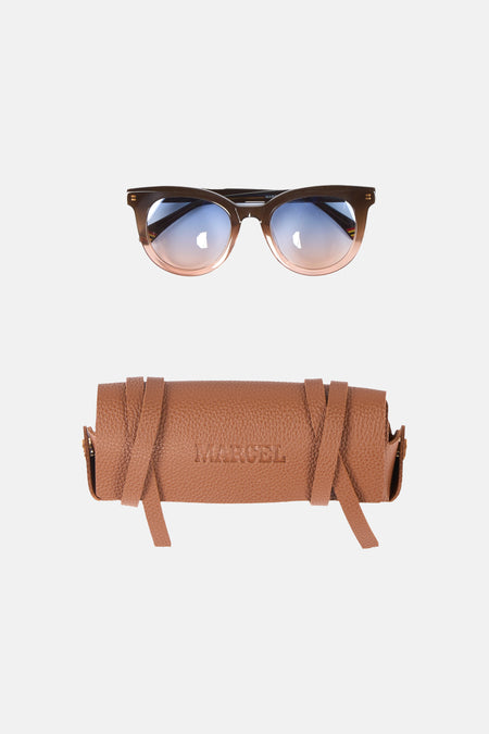 Bruine zonnebril van Le Fabuleux Marcel de Bruxelles, met blauw-roze getinte glazen en een bruine lederen brillenkoker met riempjes.