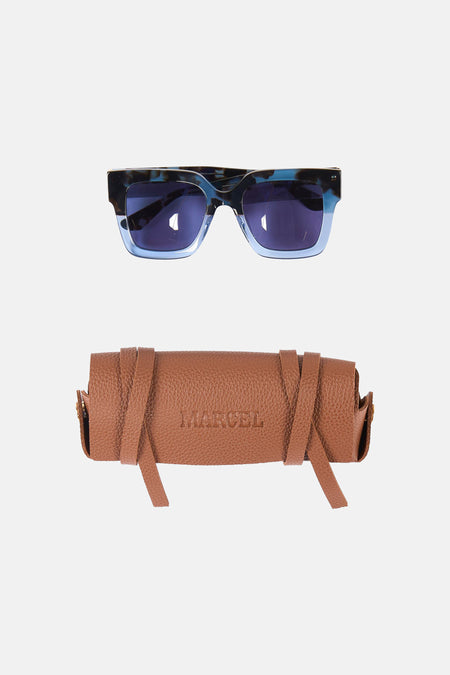 Blauwe zonnebril van Le Fabuleux Marcel de Bruxelles, met een bruine leren brillenkoker.