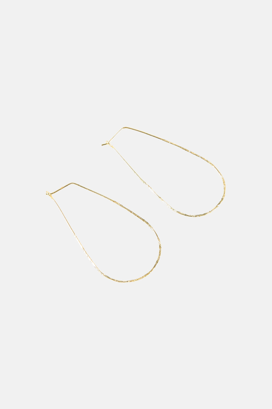 Gouden oorringen van Le Fabuleux Marcel de Bruxelles met een minimalistisch, druppelvormig ontwerp.