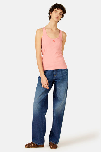 Roze geribbelde singlet van Le Fabuleux Marcel de Bruxelles met rood kreeftenborduursel, gedragen met blauwe jeans en bruine sandalen.