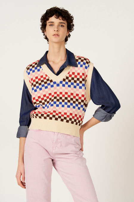 Multikleurig debardeur van Le Fabuleux Marcel de Bruxelles met een dambordpatroon, gedragen over een denim blouse en een roze broek.
