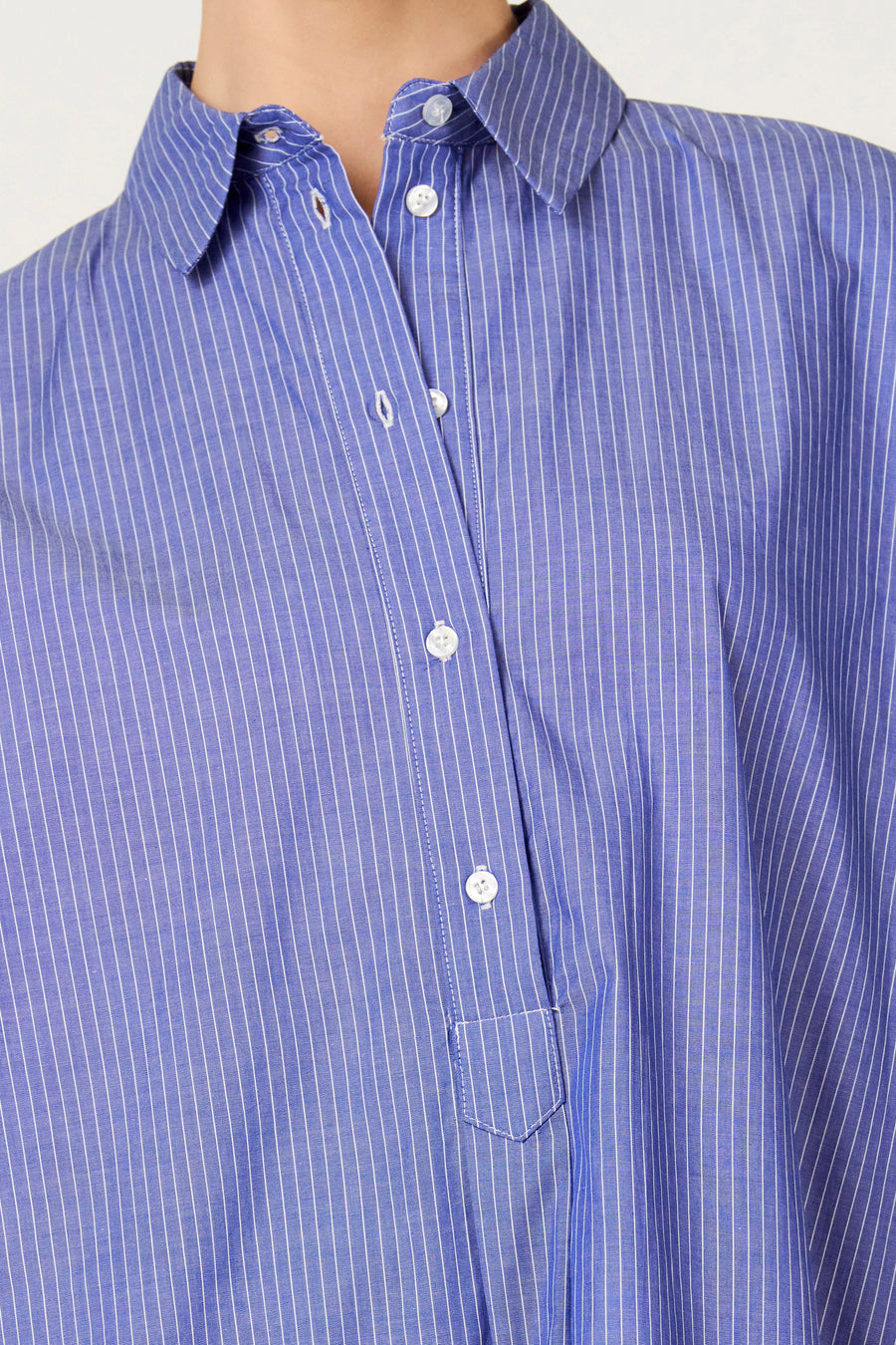 Blauwe jurk met korte mouwen van Le Fabuleux Marcel de Bruxelles, gestreept met knoopsluiting en borstzak.
